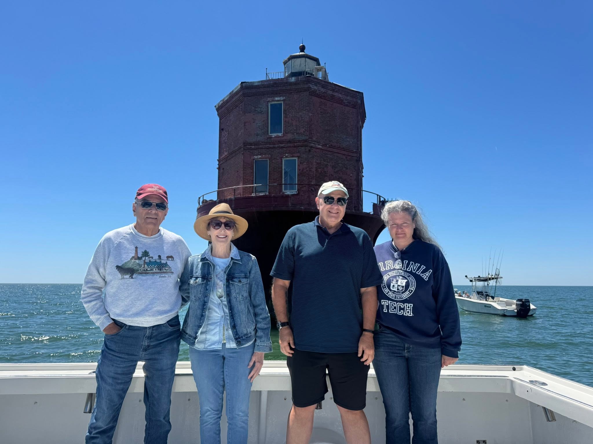 Fishing group poses on boat deck with historic lighthouse in background at Gwynn Island VA