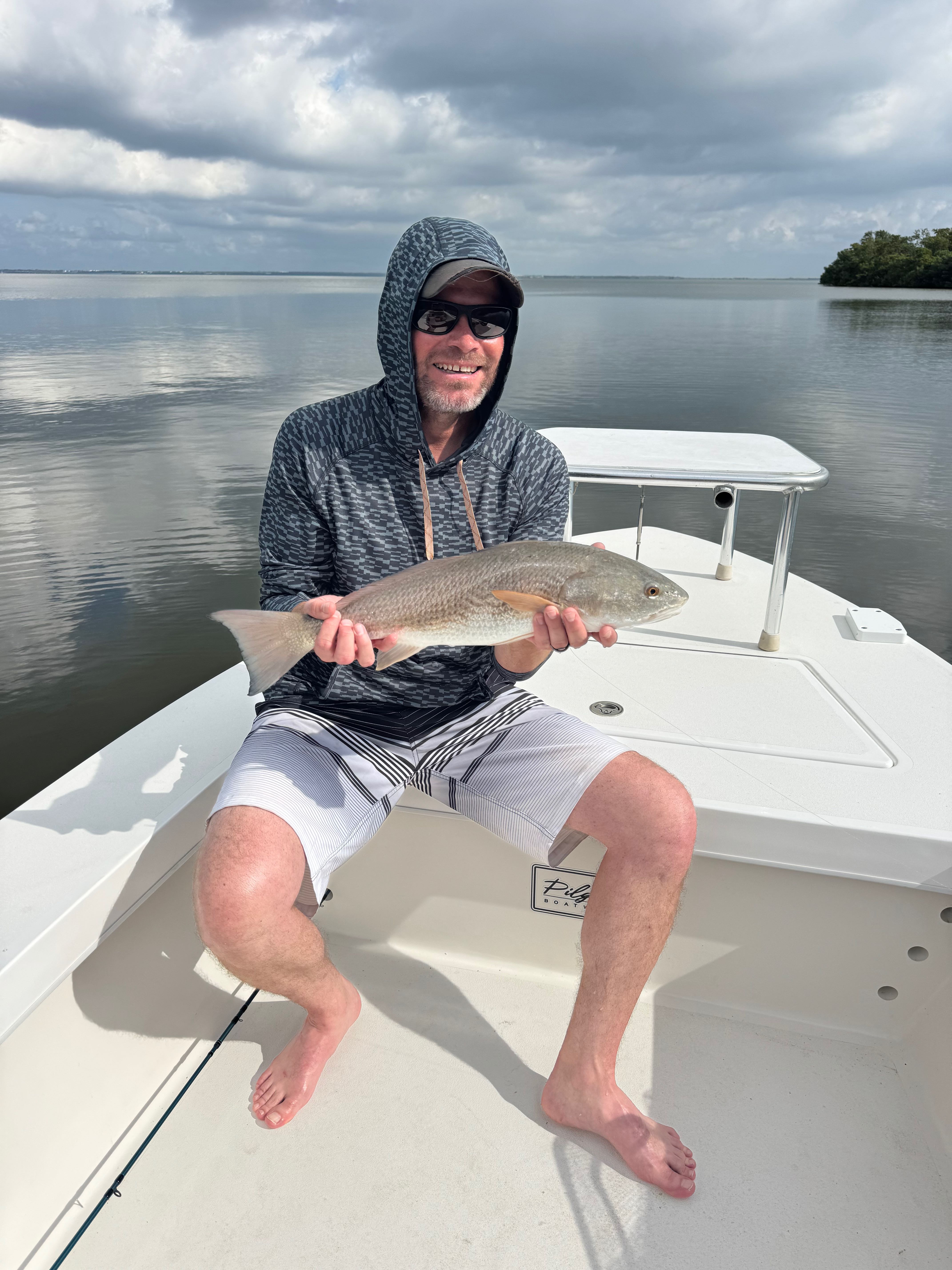 Fly fishing guide holding tarpon on shallow flats boat with fishing gear and rods
