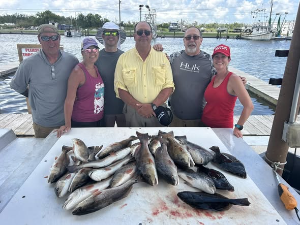 Fresh caught redfish displayed on cleaning table at Barataria LA fishing dock with marina in background