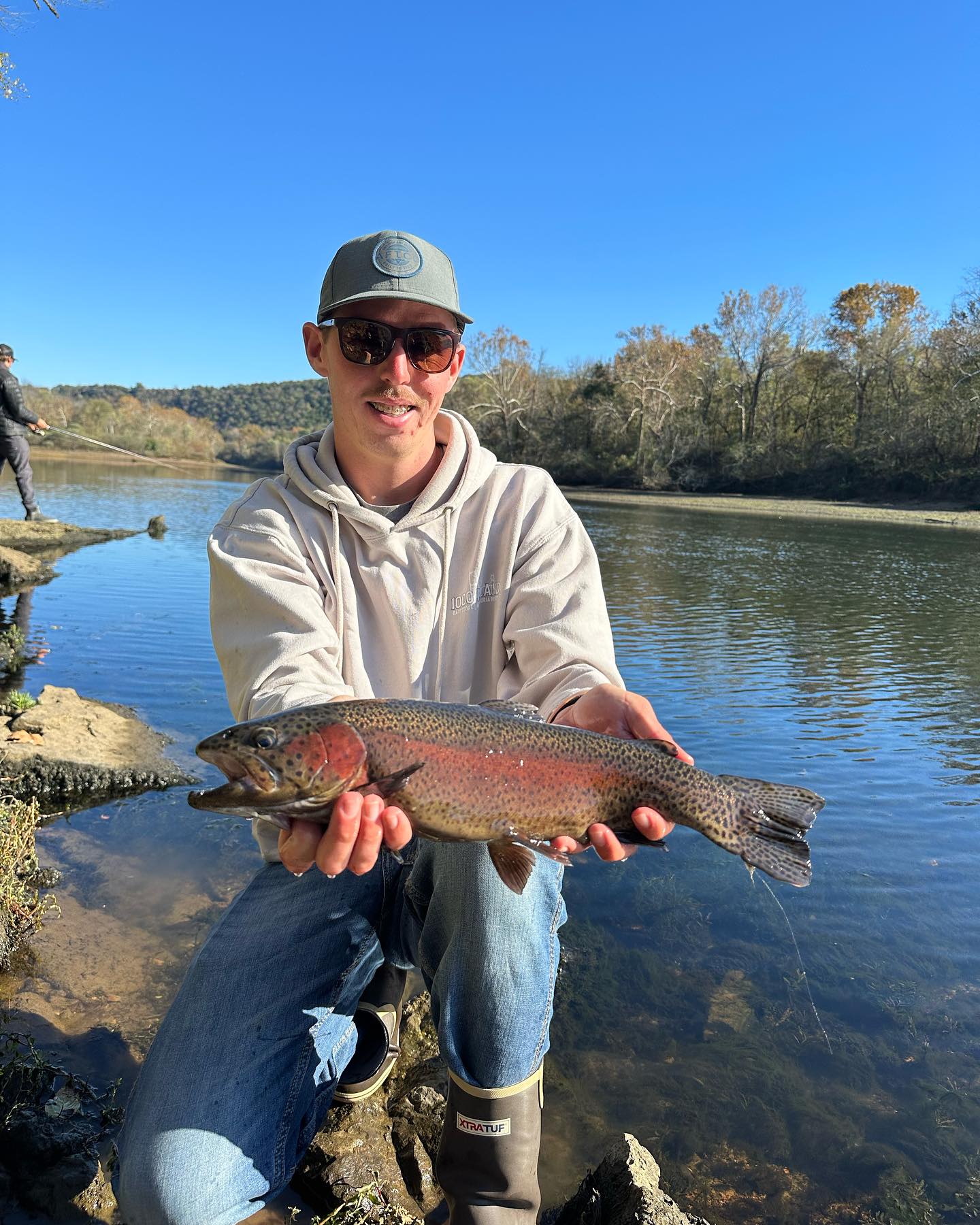 A fisherman holding a large rainbow trout in NY
