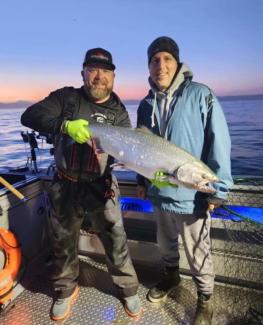 Two anglers holding a large Chinook salmon on fishing boat in Edmonds WA waters