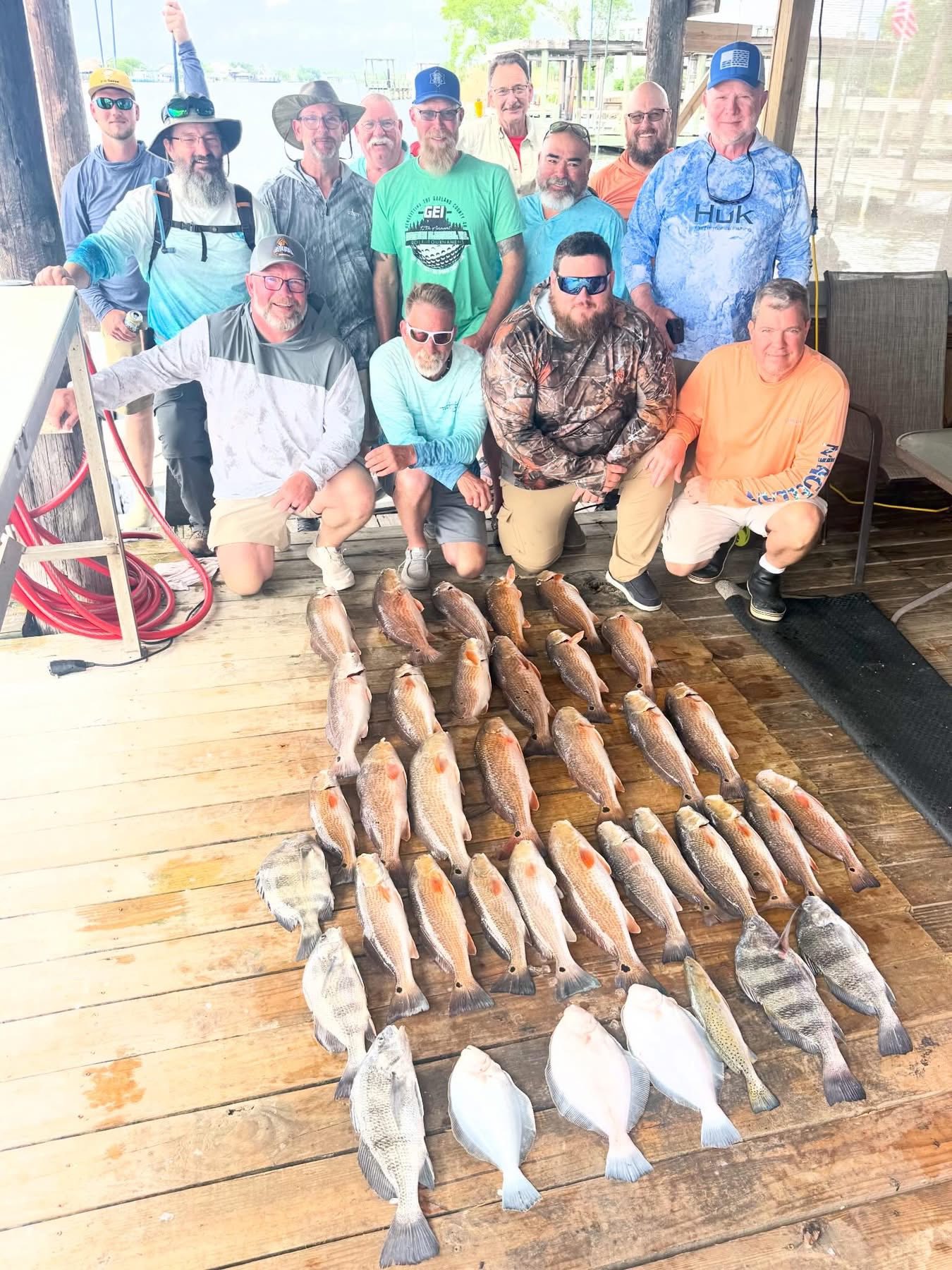 Fishing group with large catch of black drum and mixed species displayed on wooden dock in Lafitte Louisiana