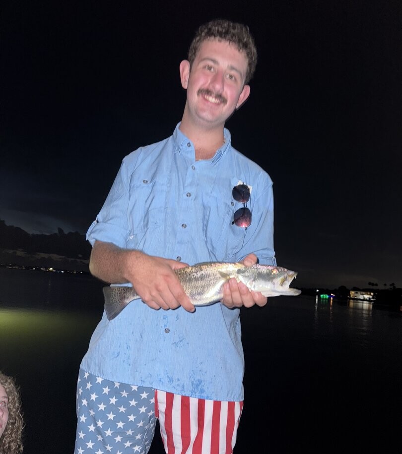 Angler holding caught fish at night in Indian Shores FL