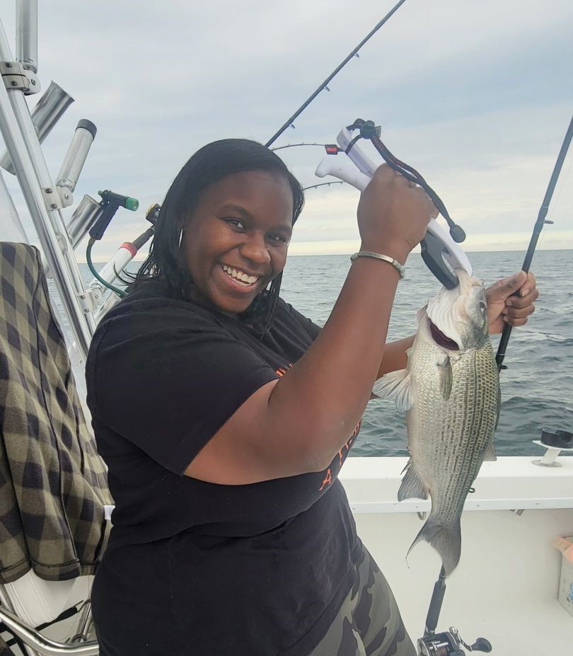 Angler holding caught striped bass on fishing boat in Buffalo NY waters