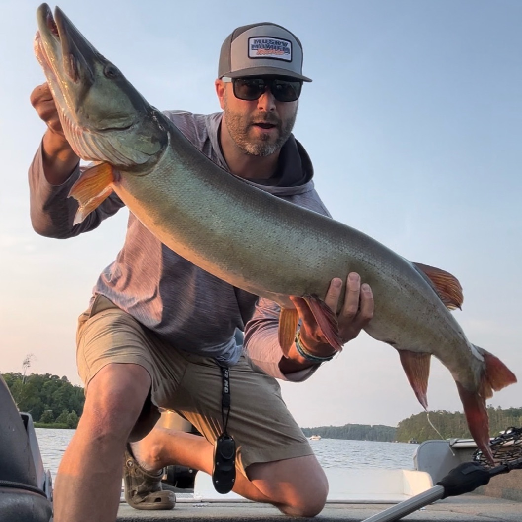 Wisconsin musky fishing charter boat on lake with guide and angler casting for musky fish