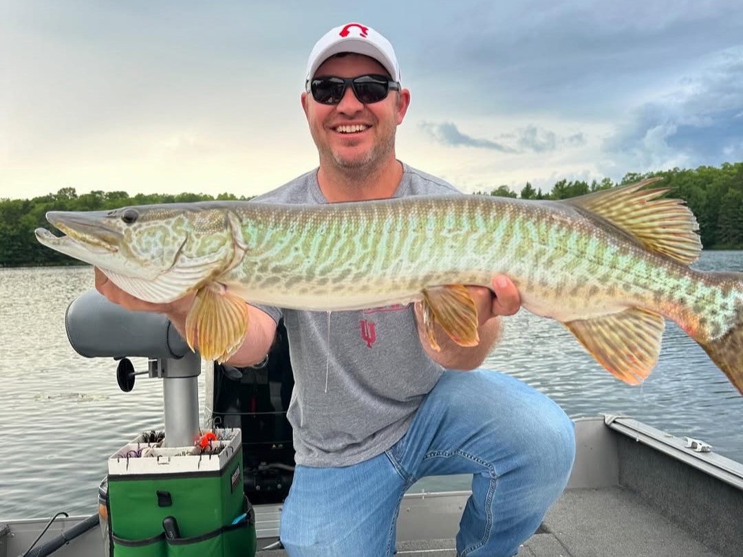 Two anglers musky fishing on Wisconsin lake with professional guide and boat equipment