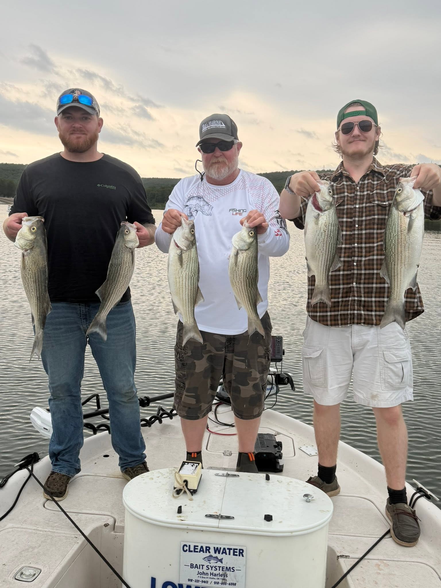 Three anglers displaying striped bass catch on fishing boat in Mannford OK