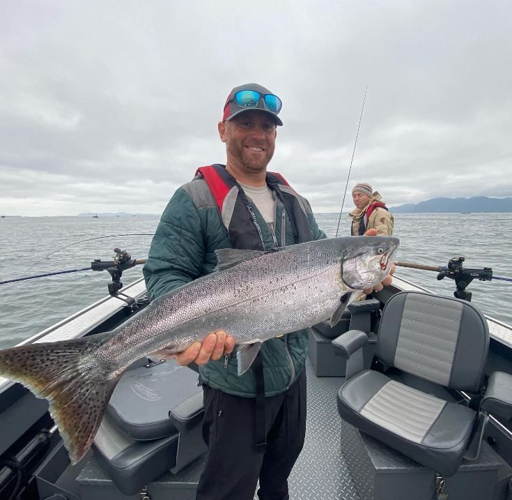 A rainbow trout being held by two people in OR