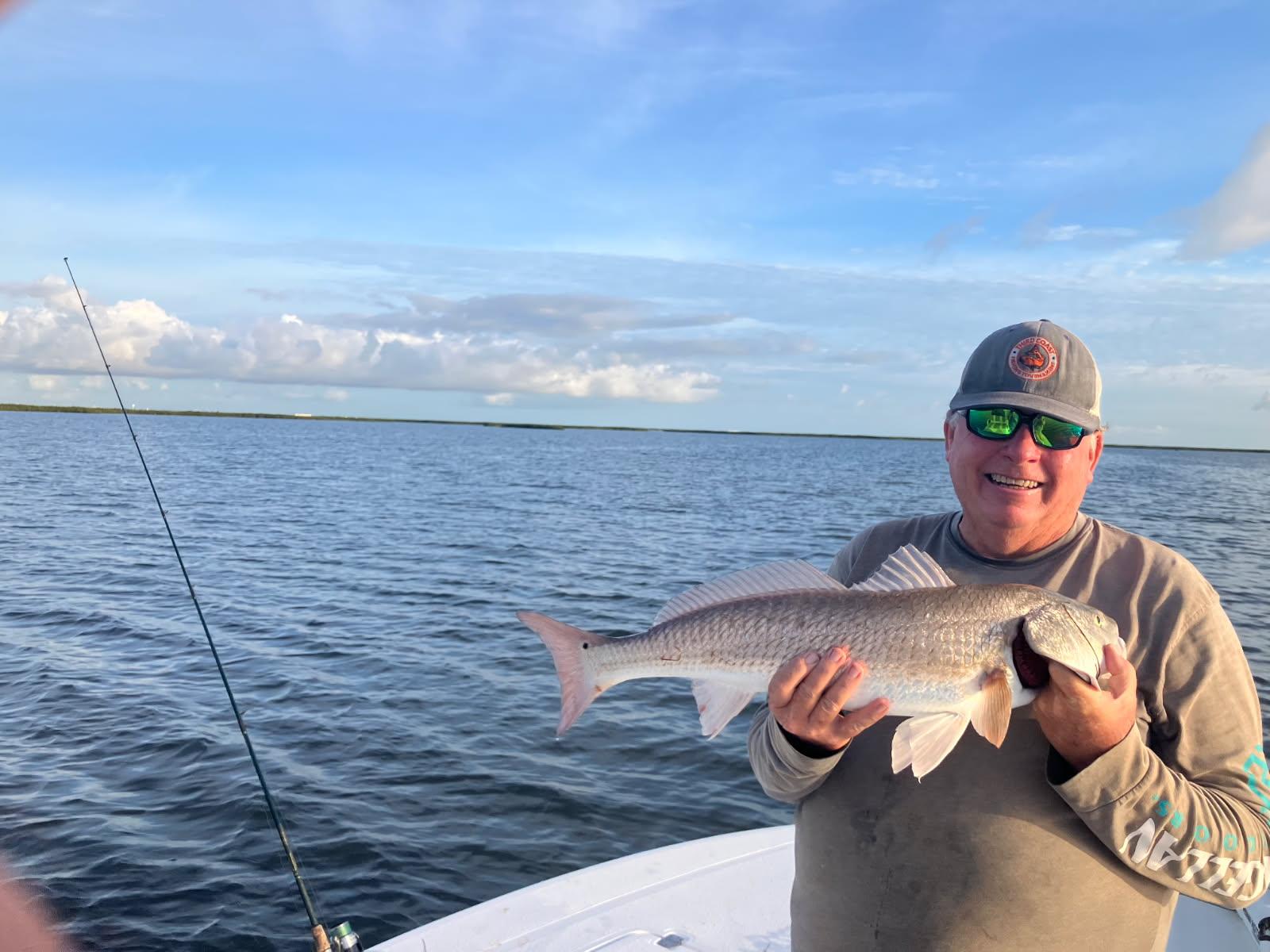 Angler holding freshly caught redfish on fishing boat in Port Aransas TX waters