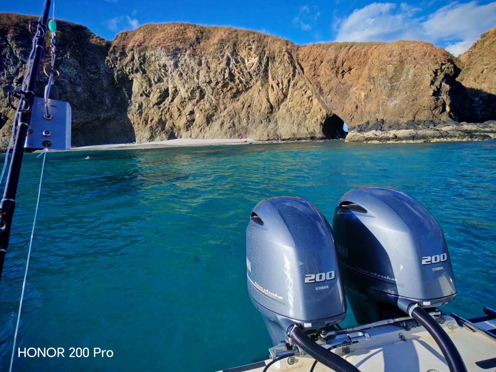 Twin outboard motors on fishing boat in turquoise waters near rocky cliffs in Guanacaste