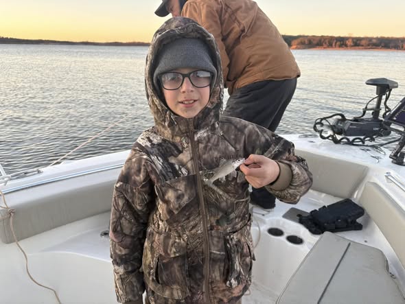 Young angler on fishing boat at Sand Springs OK during sunset on calm water