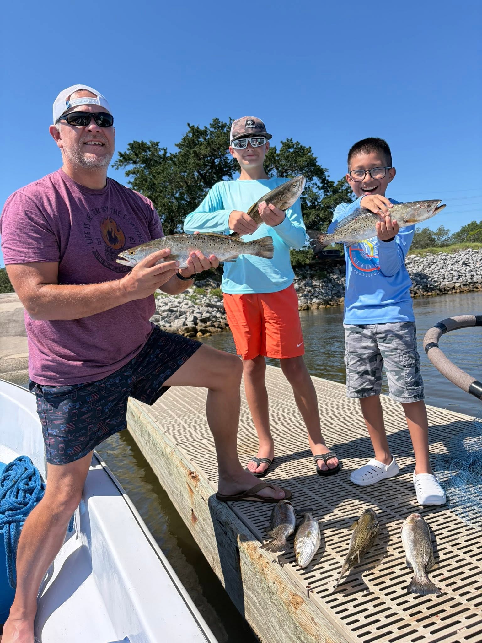 Successful fishing trip in Gulf Shores AL with speckled trout and redfish catch displayed on dock