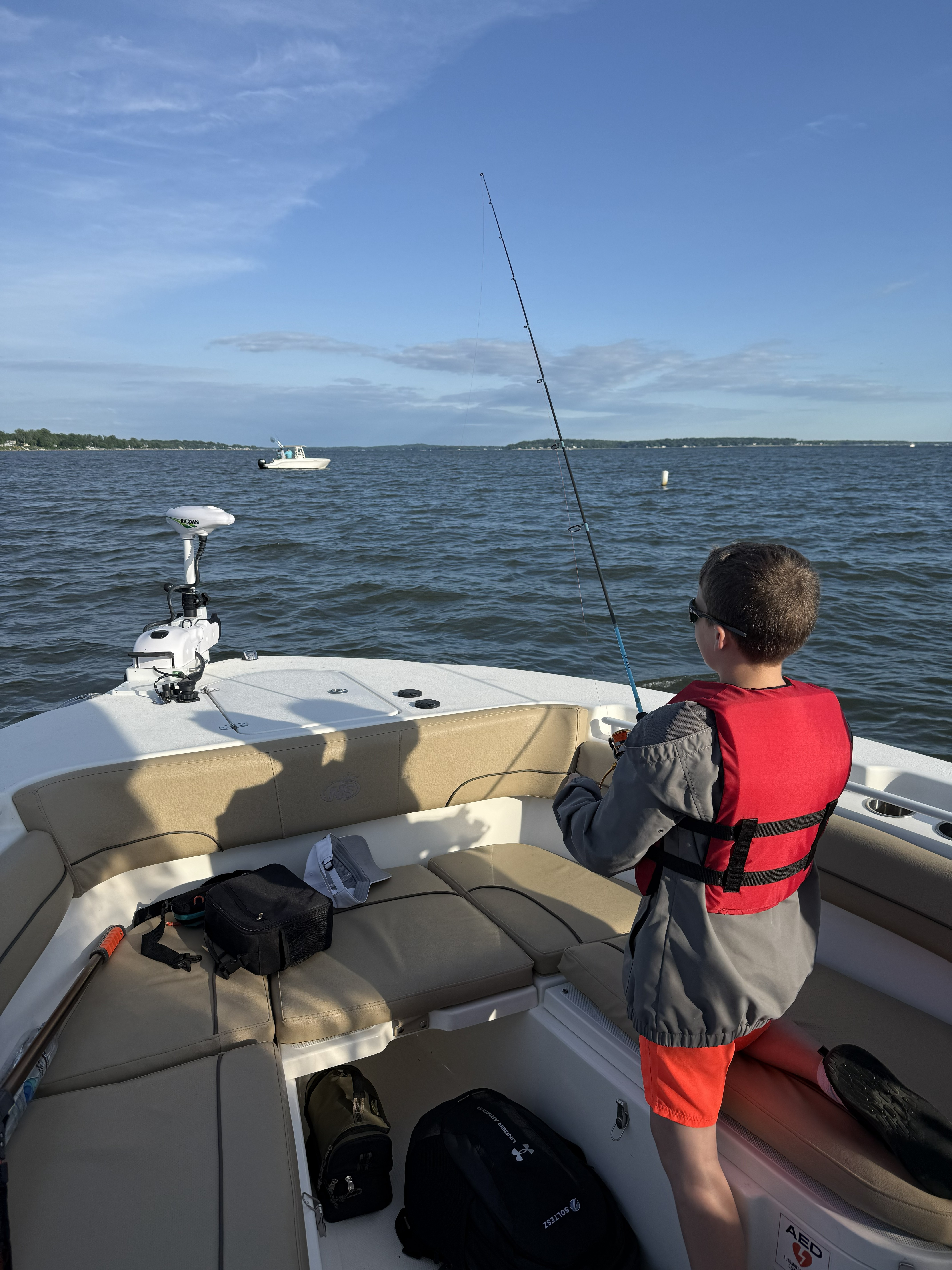 Fishing from boat on water in Pasadena MD with fishing rod extended