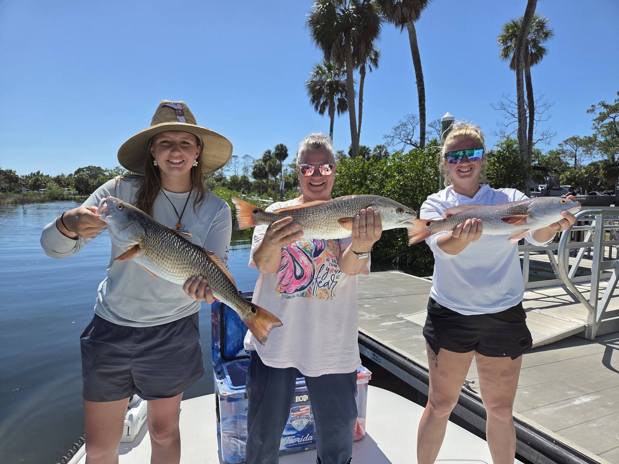 Three redfish caught during fishing trip in Bayport FL displayed on boat dock