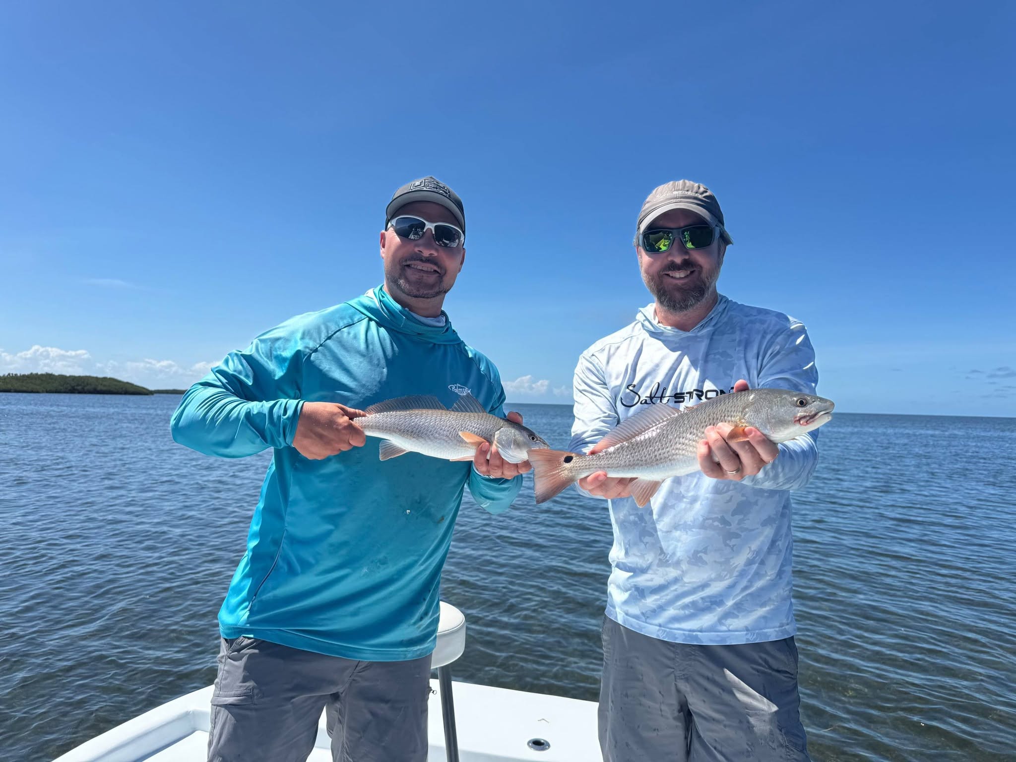 Two anglers displaying caught redfish on fishing boat in Daytona Beach FL waters