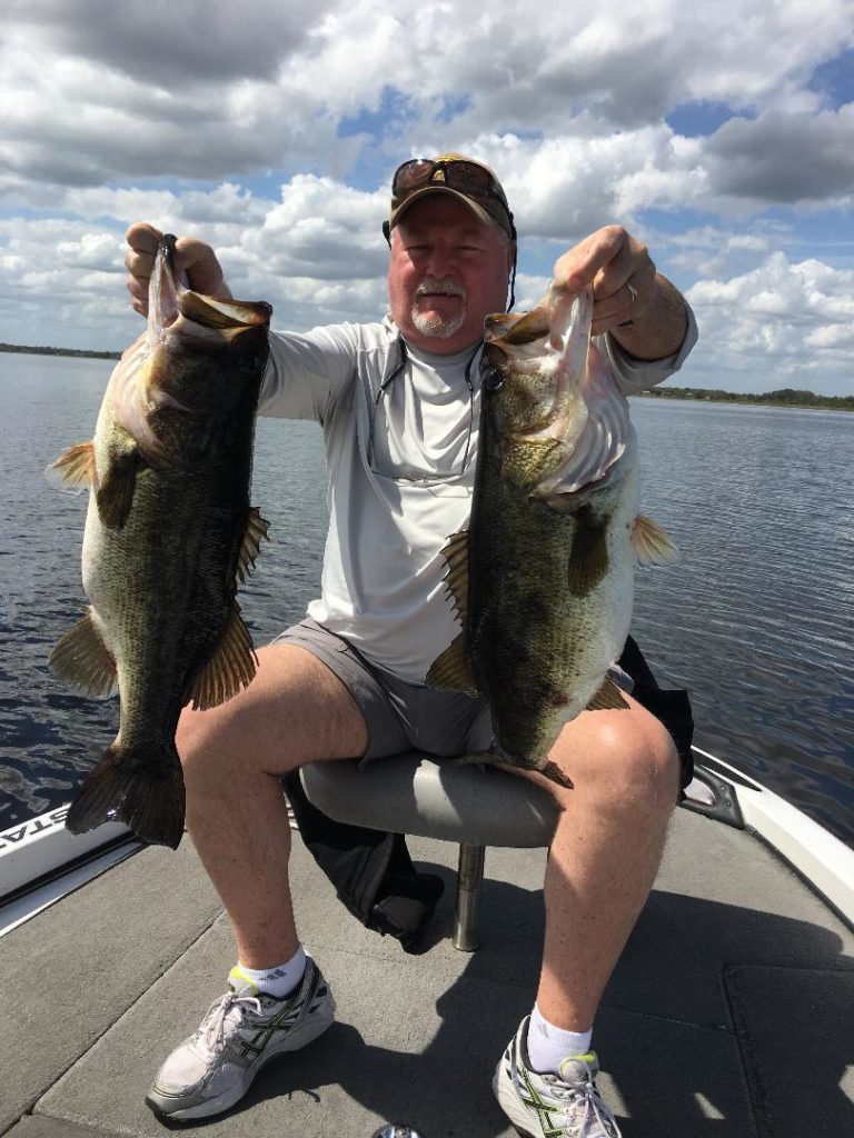 Angler holding two largemouth bass caught in FL