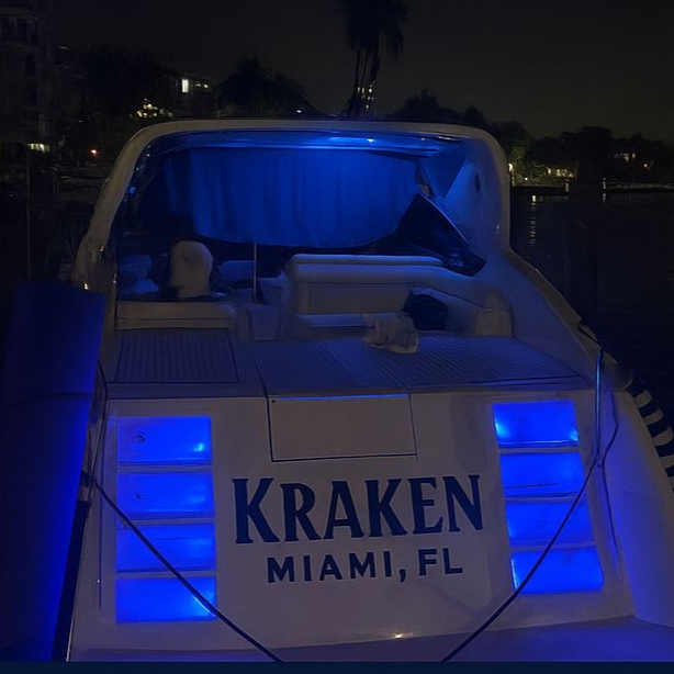Miami luxury yacht at night with city skyline lights reflecting on Biscayne Bay waters