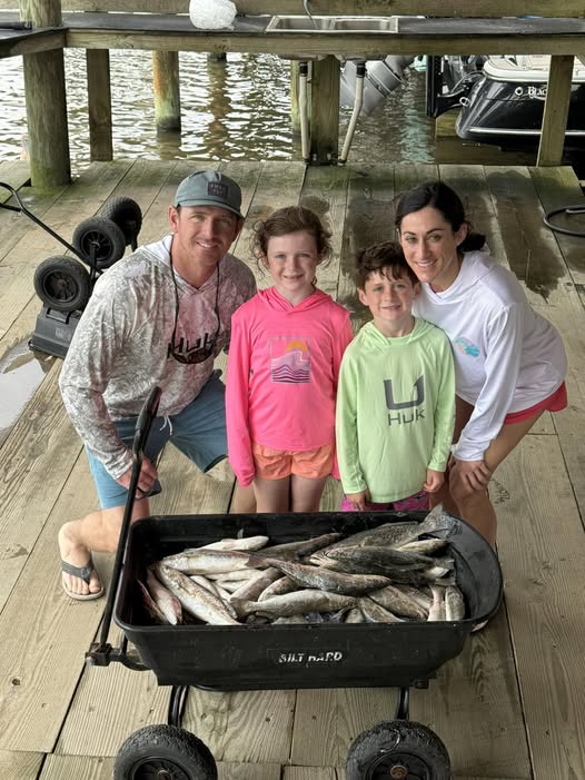 Family fishing trip in Golden Meadow LA with wagon full of fresh caught fish on wooden dock