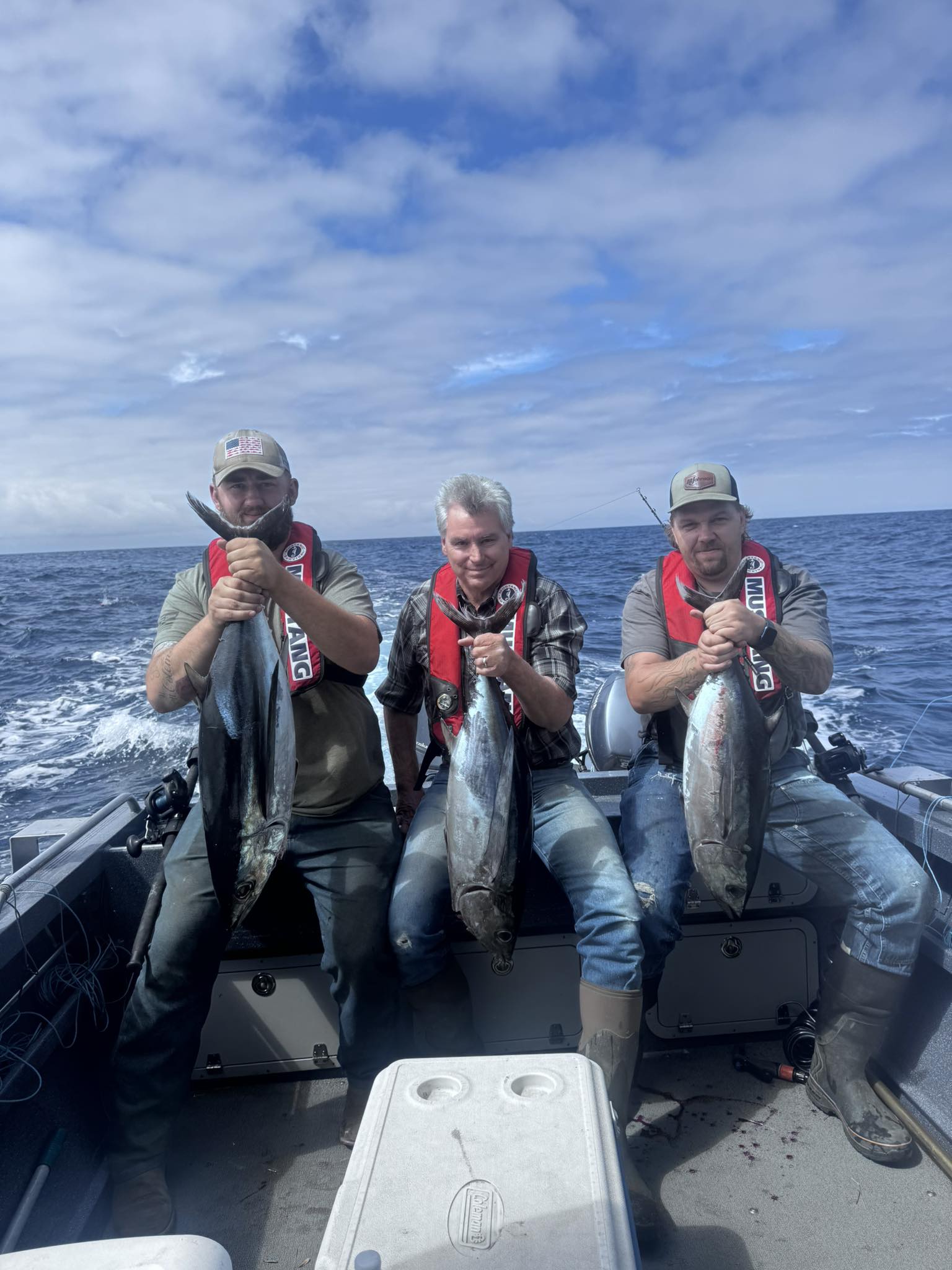 Three anglers displaying fresh caught bluefin tuna, albacore tuna, and yellowfin tuna on fishing boat off Charleston Oregon