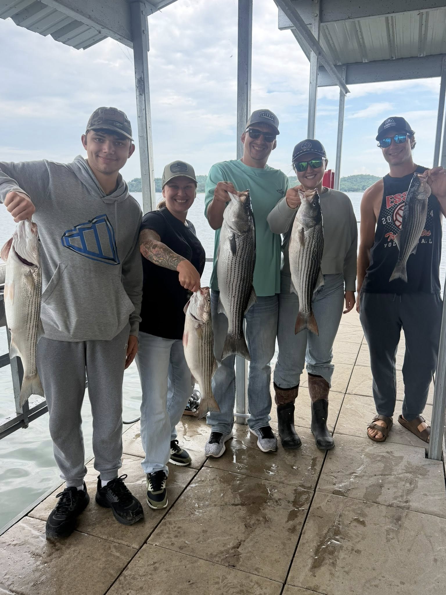 Five striped bass caught during fishing trip in Rogers AR displayed on dock