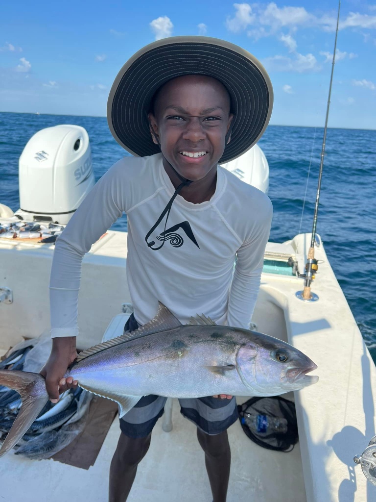 A fisherman holding a large greater amberjack fish in FL