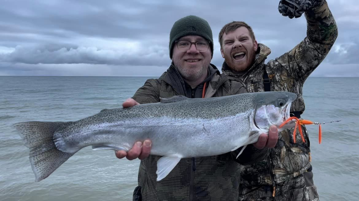 Fisherman proudly holding a large rainbow trout in Port Huron