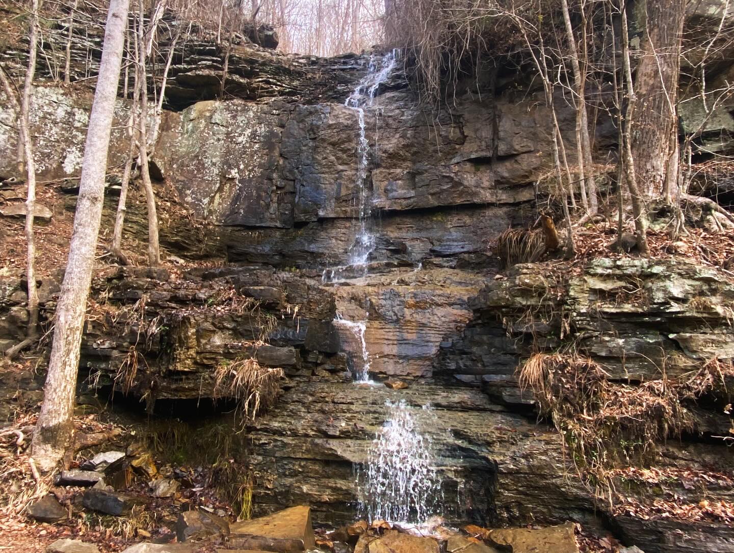 Waterfall cascading down layered rock formation in Chattanooga Tennessee forest setting