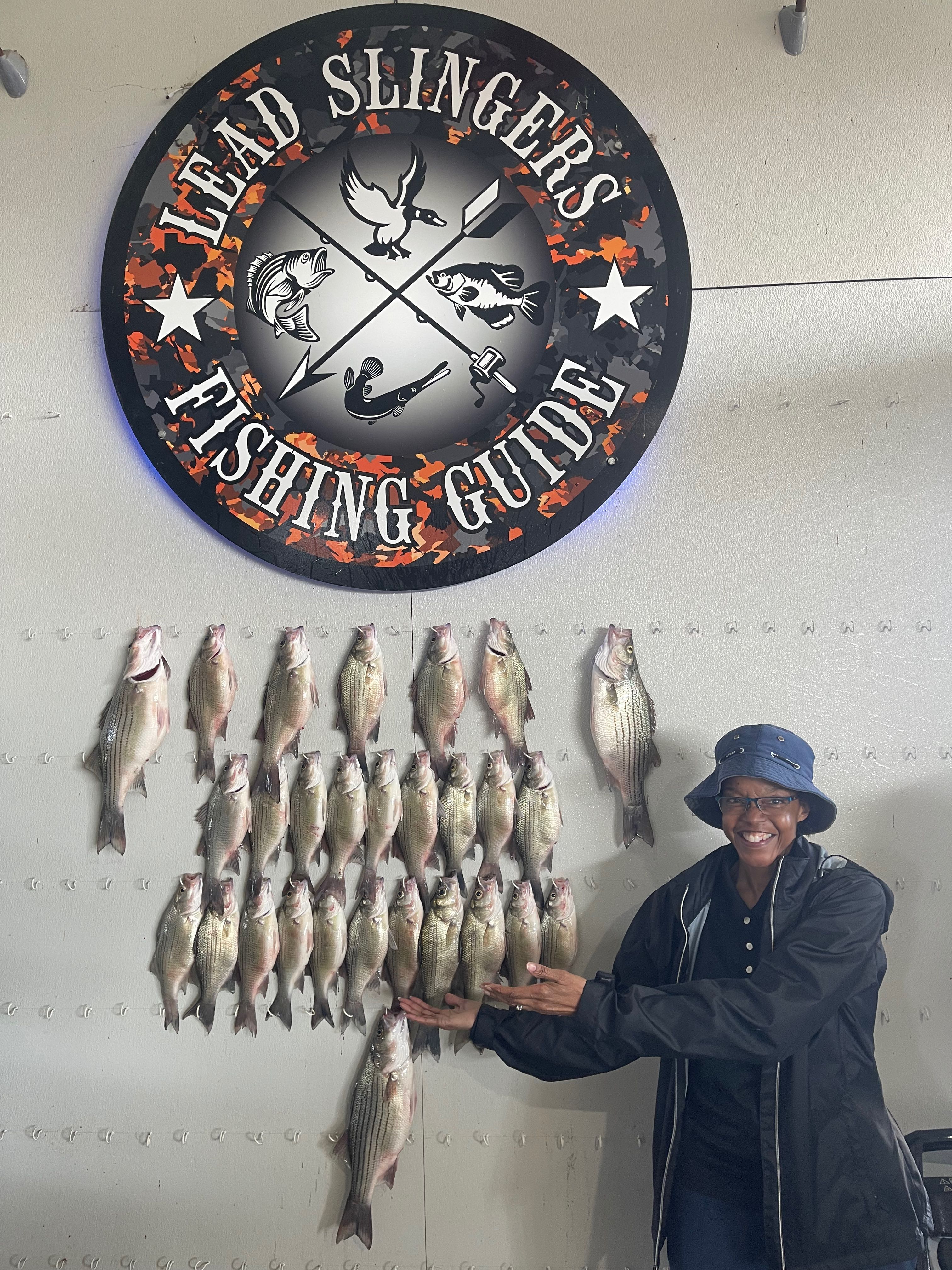 Large display of caught striped bass hanging on wall beneath fishing guide business sign in Forney TX