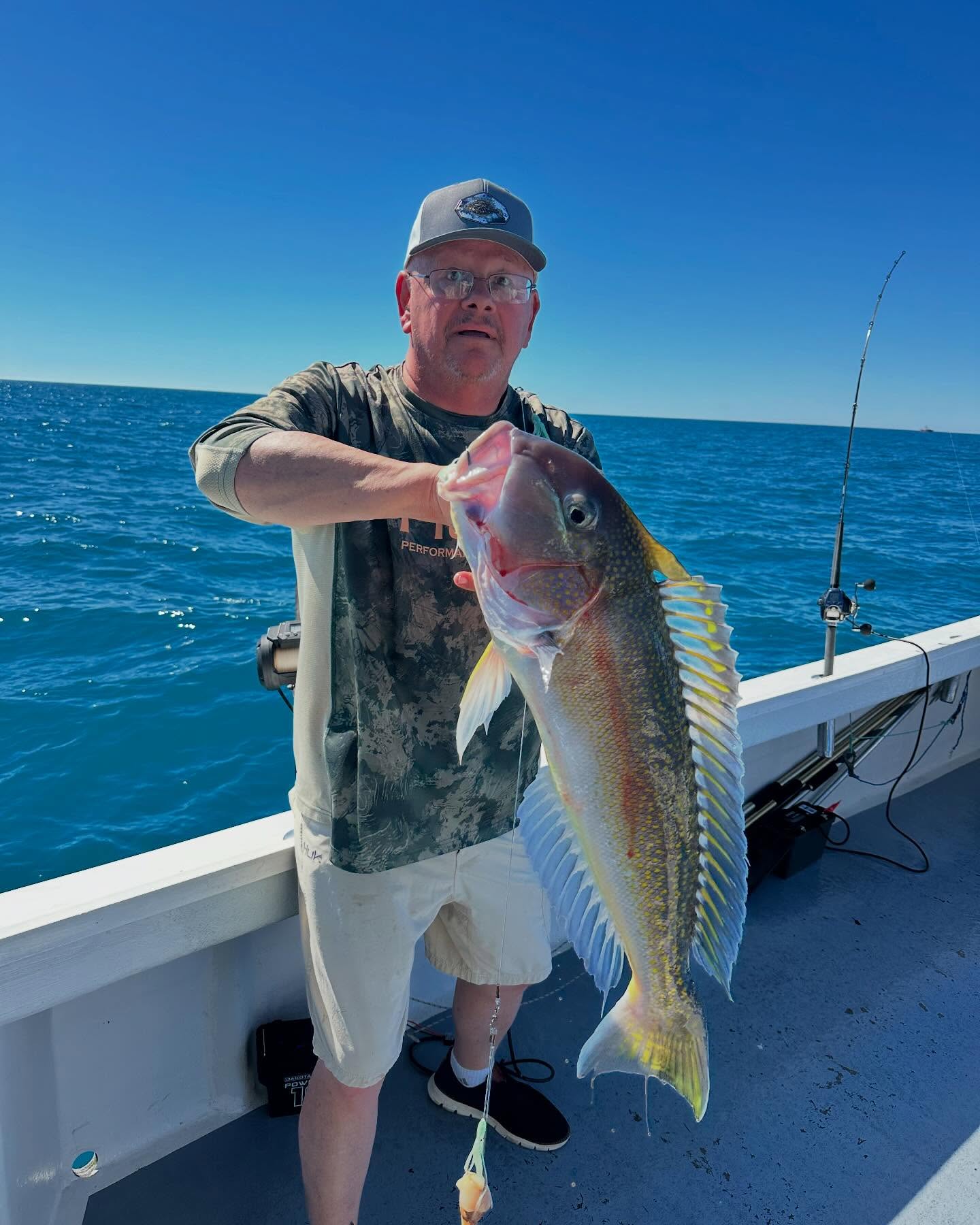Angler holding large fish catch on fishing boat in Neptune City NJ waters