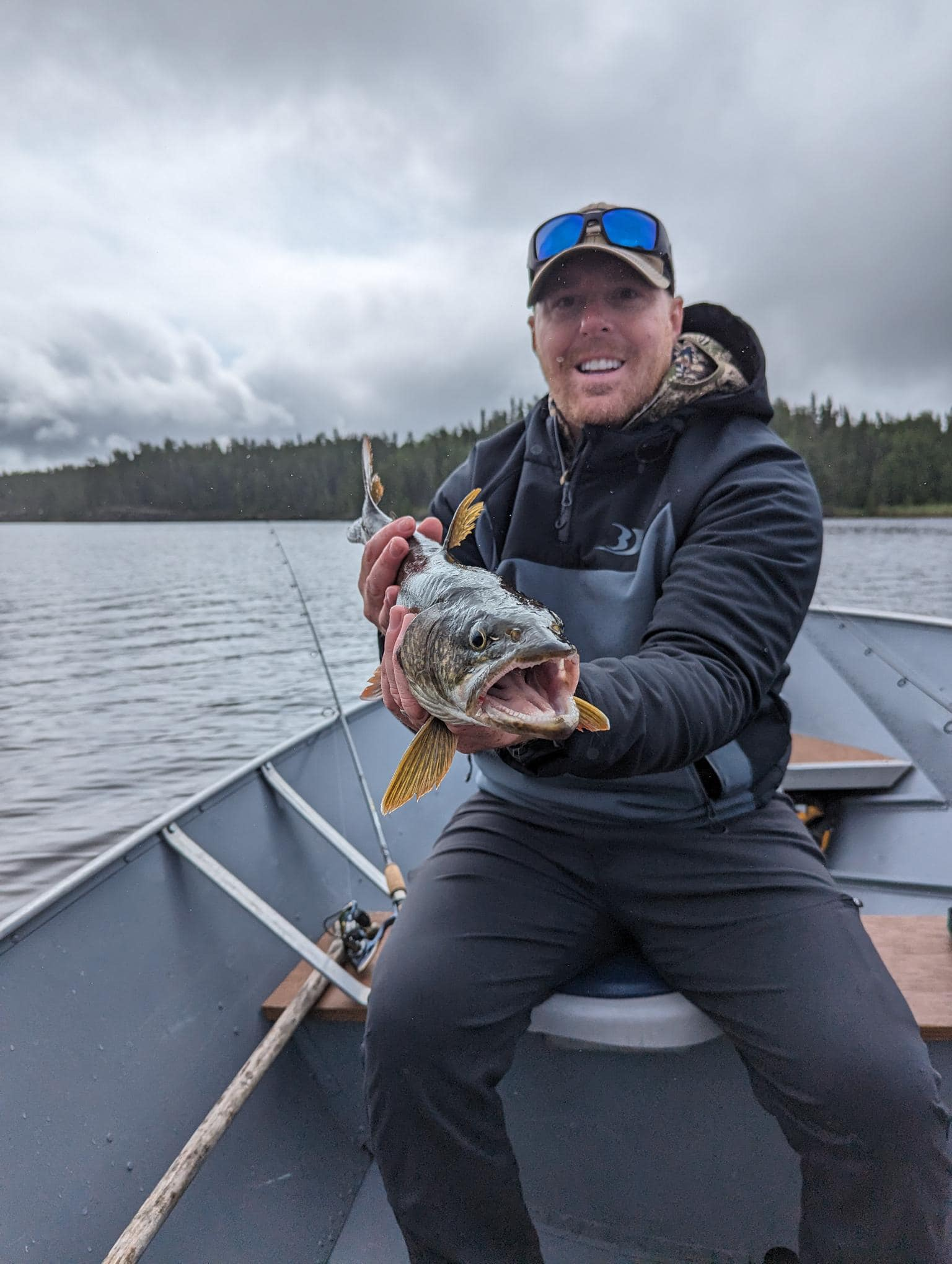 A fisherman holding a 9-inch fish at Savant Lake