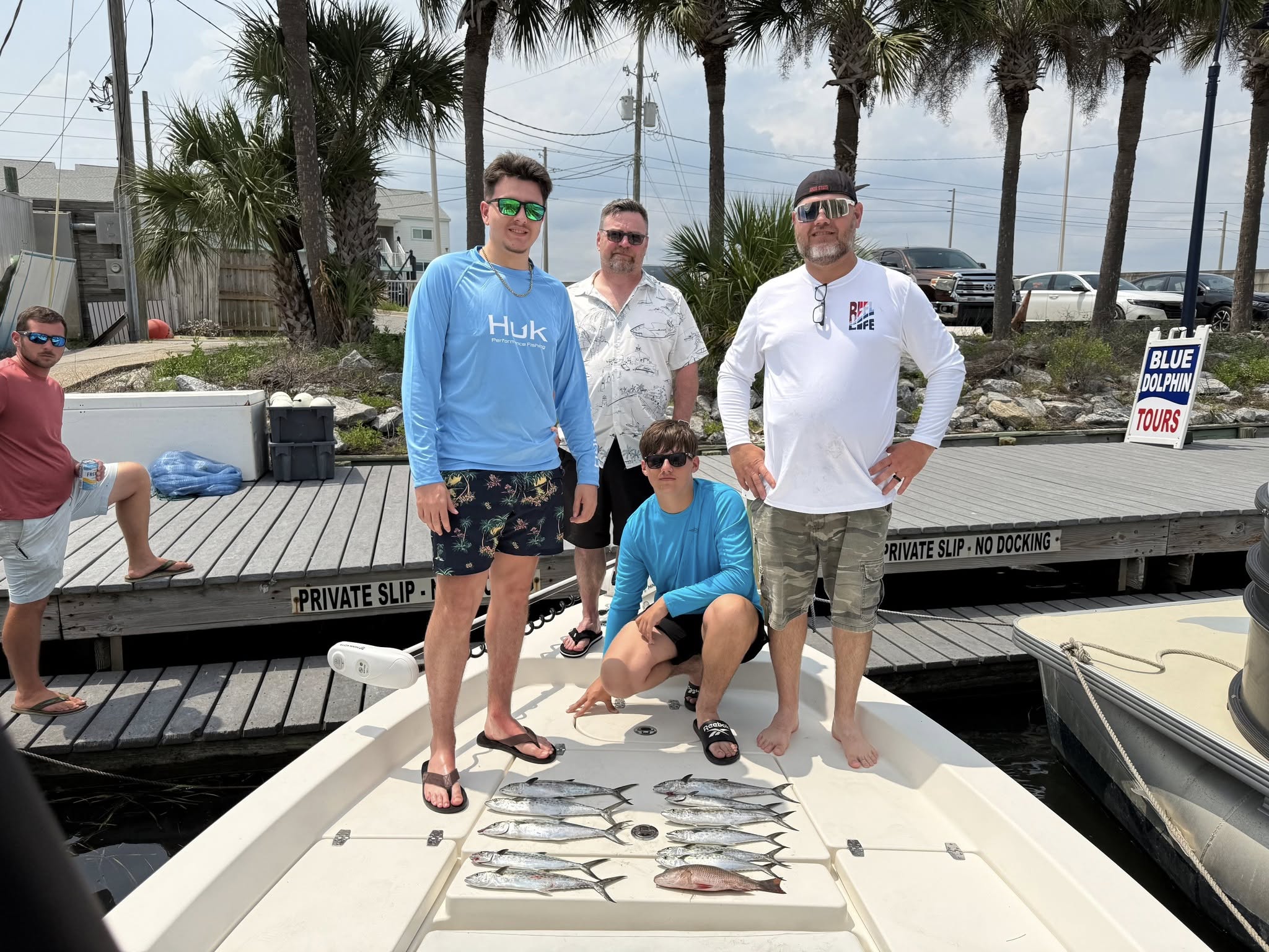 Fishing charter group displays mixed species catch on boat deck at Panama City FL marina with palm trees