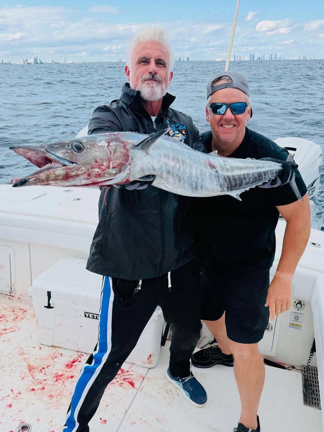 Two anglers holding large wahoo fish on fishing boat deck in New York City waters