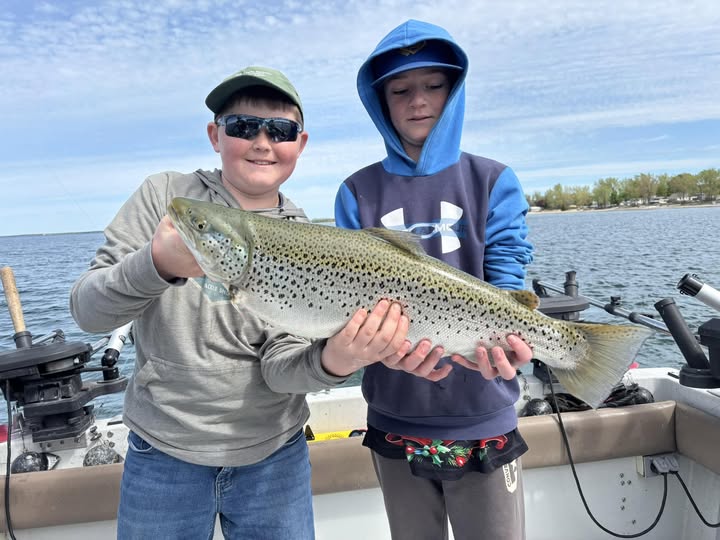 Two anglers holding a large brown trout on fishing boat in Ogdensburg NY