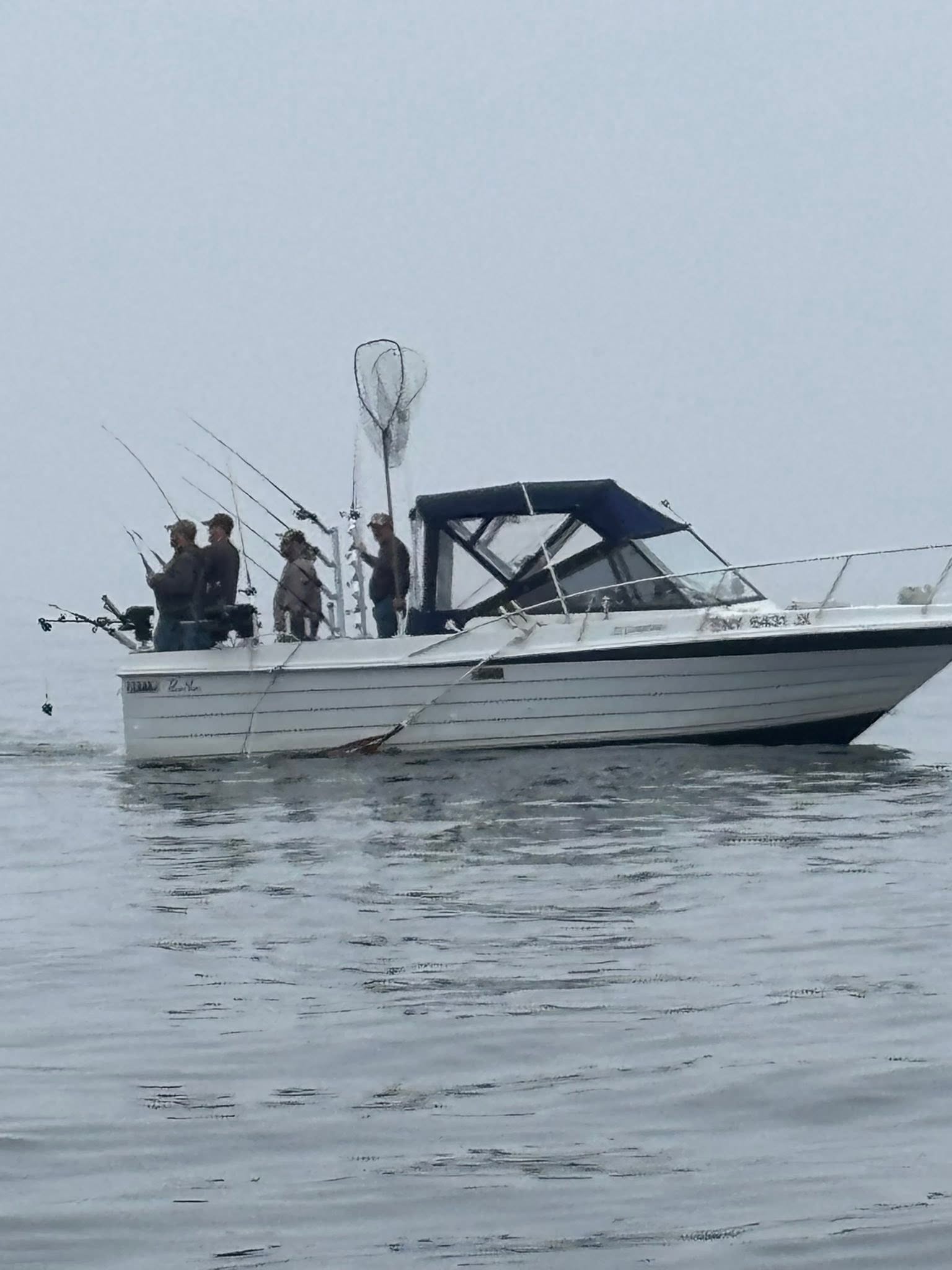 White fishing boat with multiple fishing rods on calm water in Ogdensburg NY