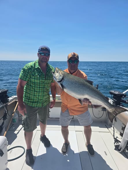 Two anglers holding a large Chinook salmon on a fishing boat in Ogdensburg NY