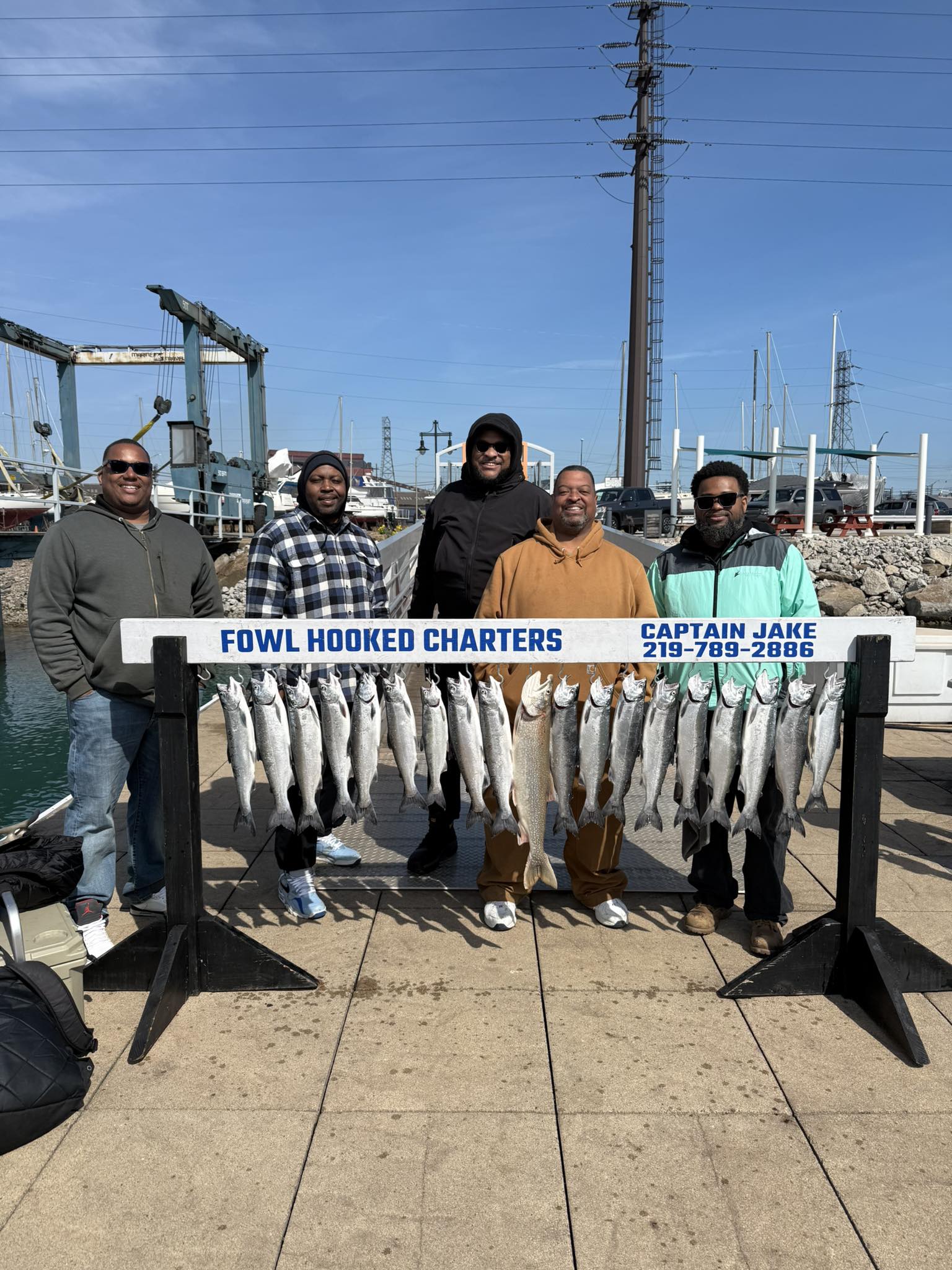 Successful coho salmon fishing charter displaying catch at East Chicago IN marina with boats and dock infrastructure