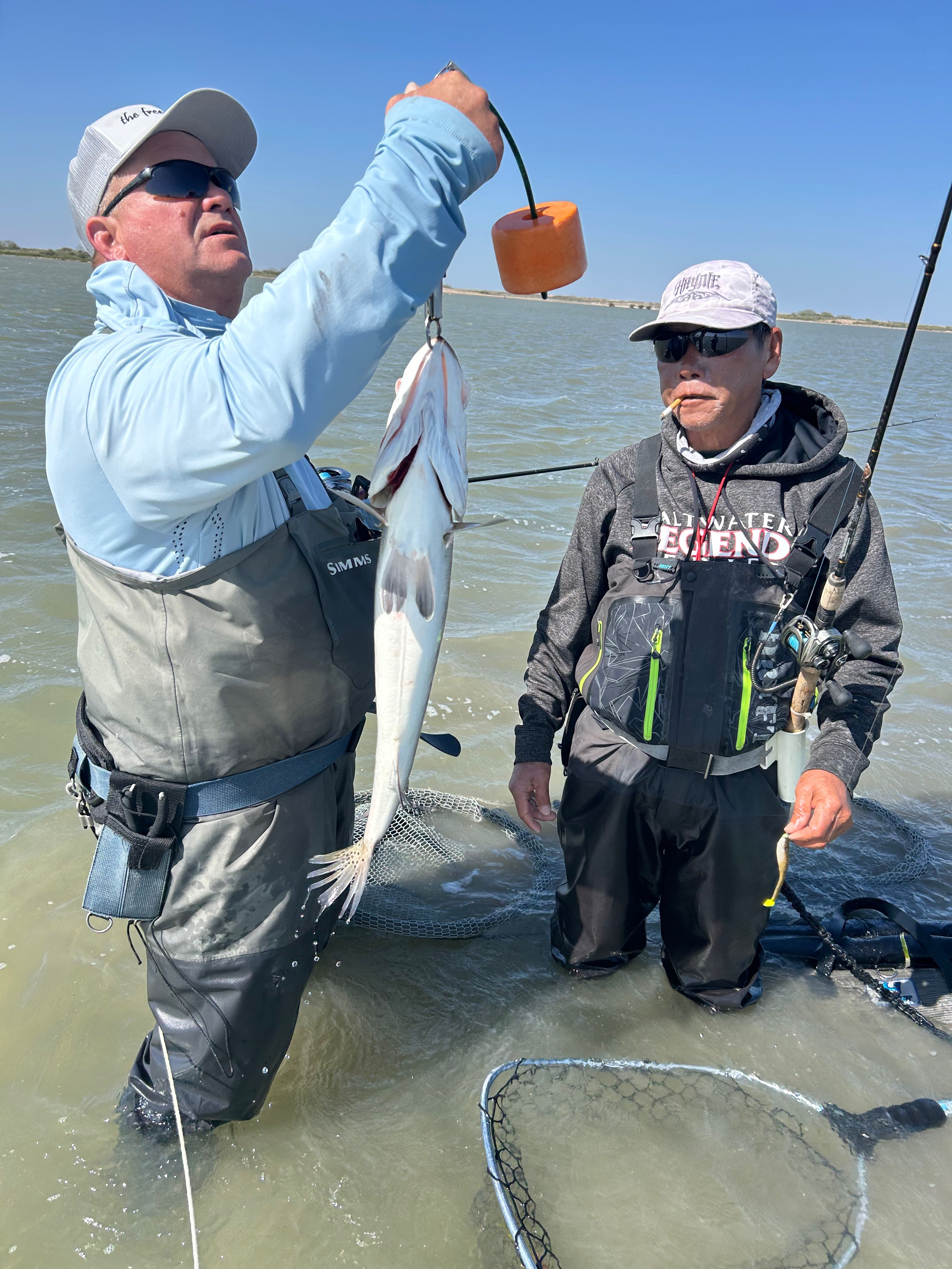 Angler holding caught fish while wade fishing in shallow water near Rockport TX