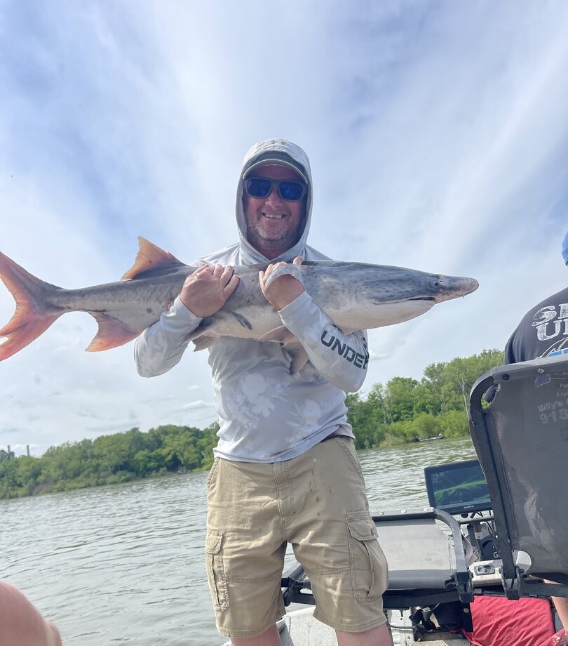 Angler holding freshly caught fish on boat in Sand Springs OK