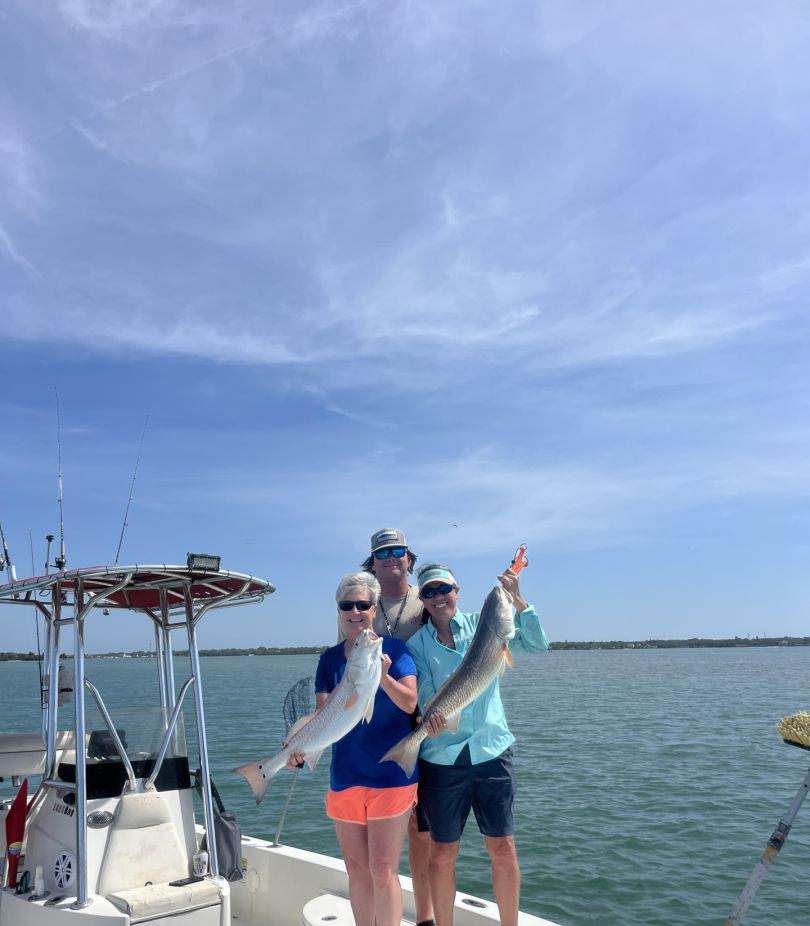3 anglers holding 2 large fish on the shores of Indian Shores