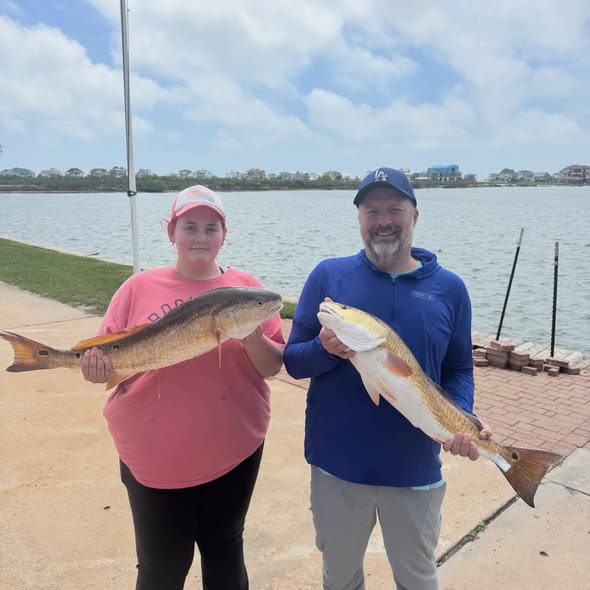 Two anglers displaying caught redfish at League City TX waterfront