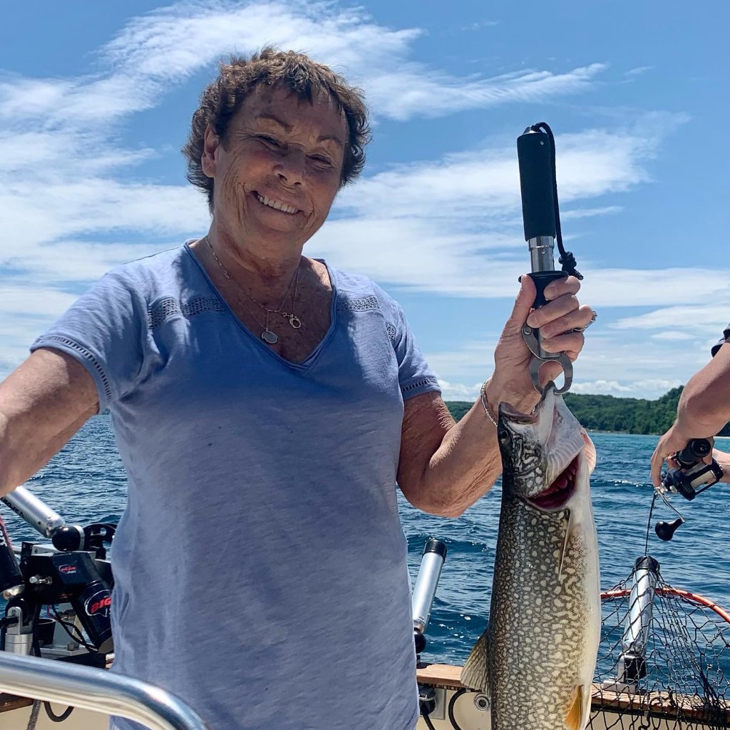 Angler holding a 12-inch lake trout caught in MI