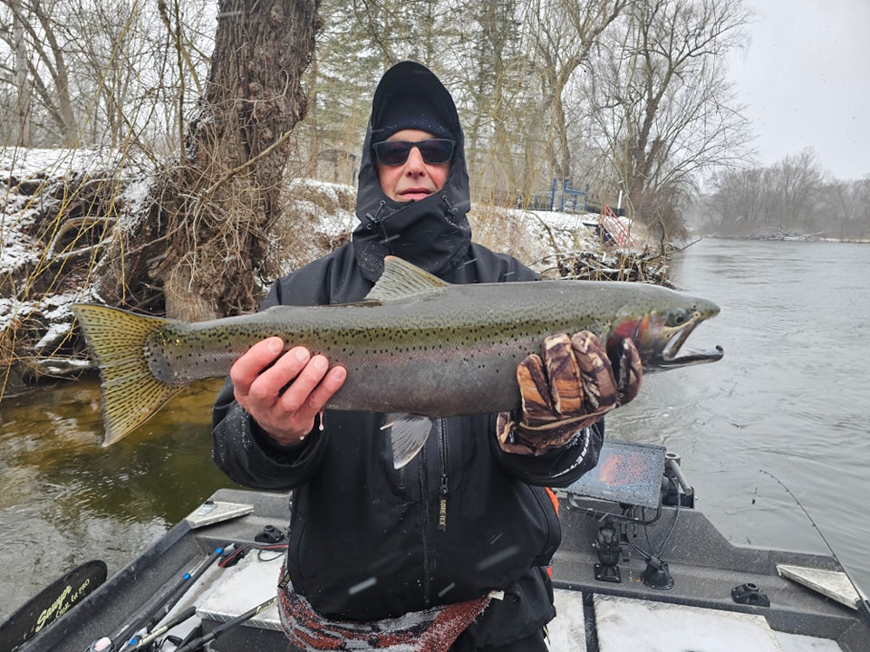 A happy angler holding a large rainbow trout in Newaygo
