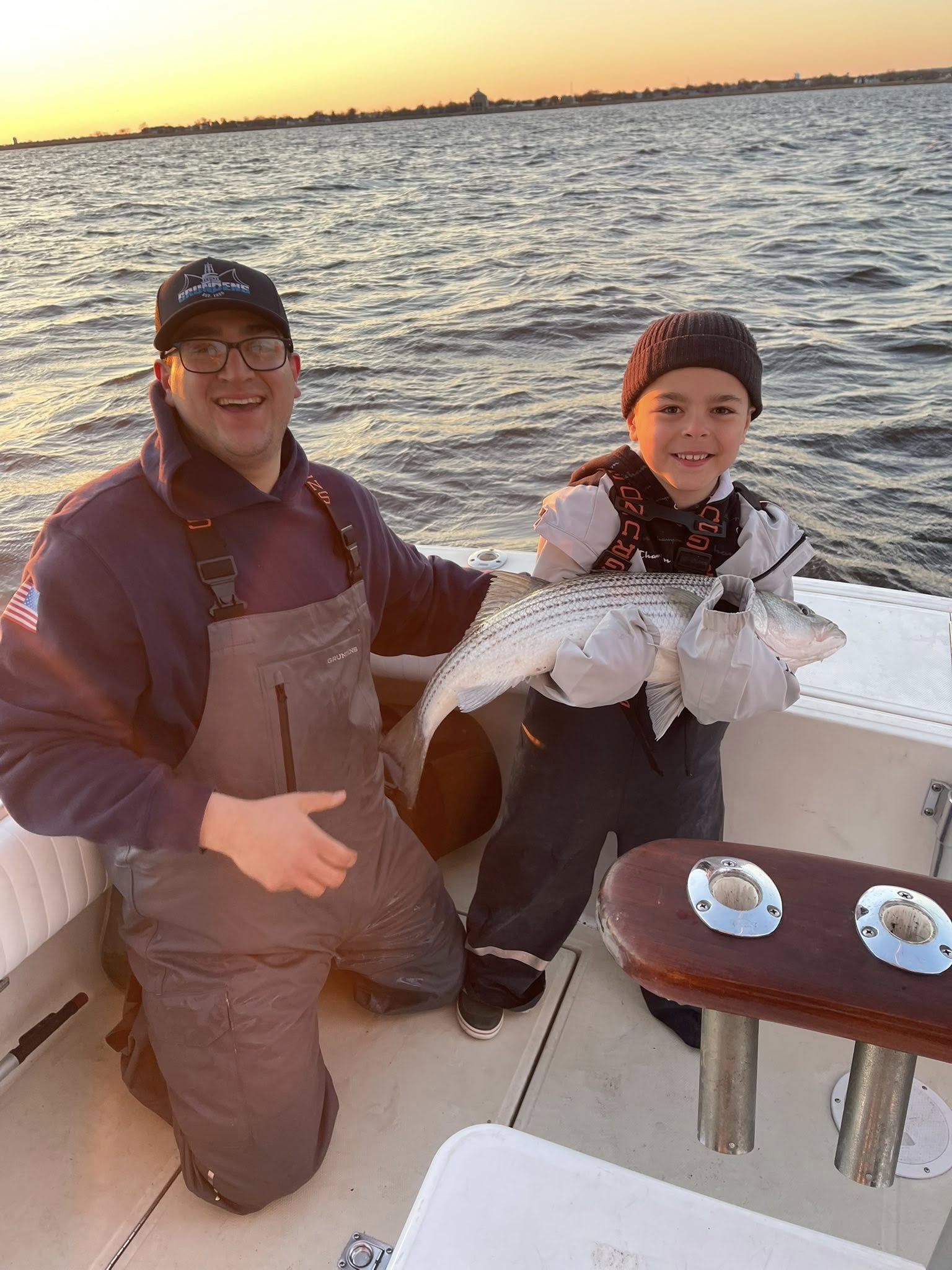 Successful fishing trip on boat with striped bass catch in Keyport NJ waters at sunset