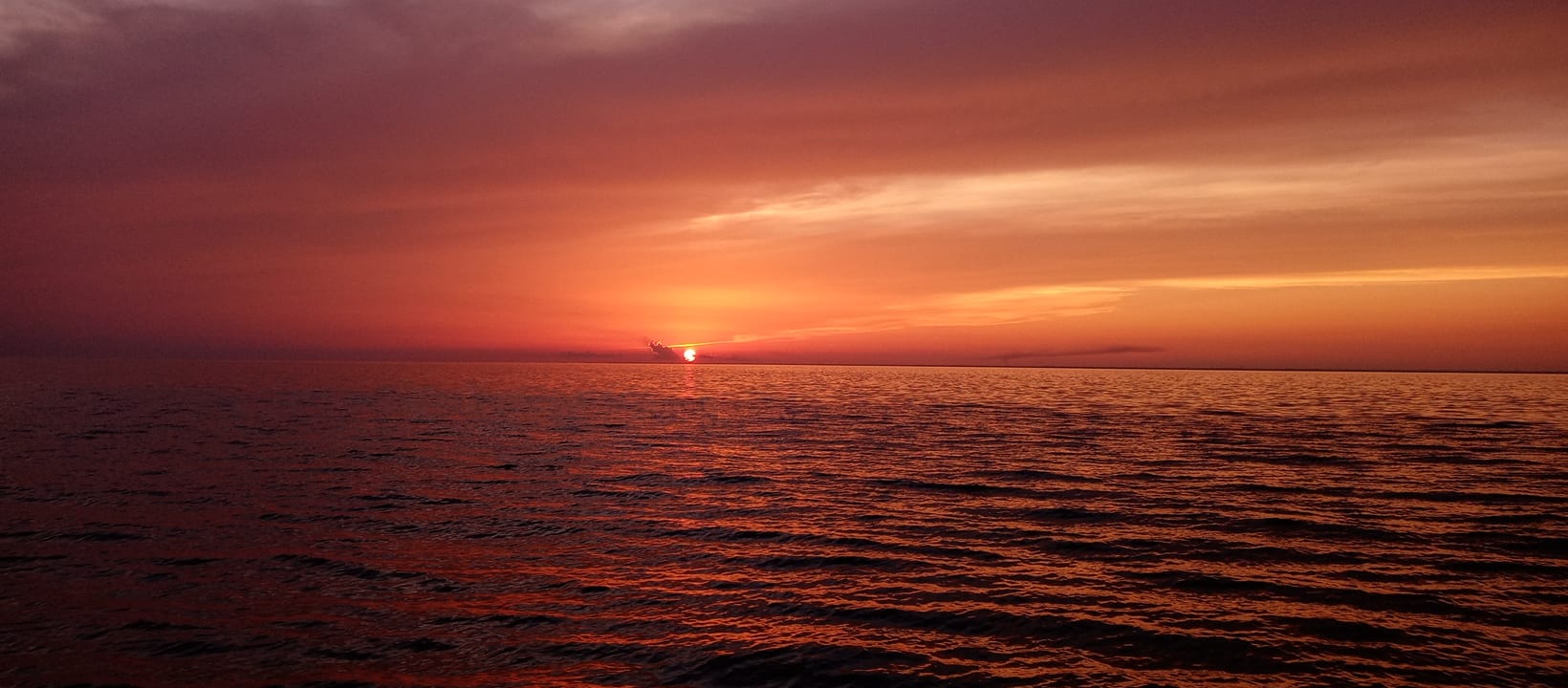 Sunset cruise boat on Mississippi Gulf Coast waters near Gulfport with orange sky reflection