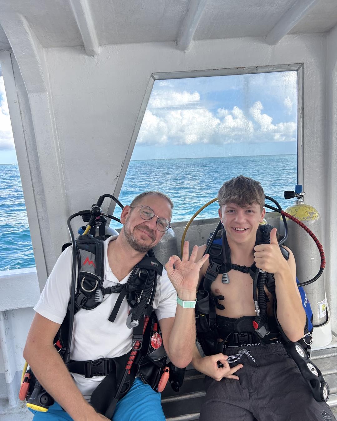 Scuba divers in full gear preparing for underwater dive from boat deck on open ocean