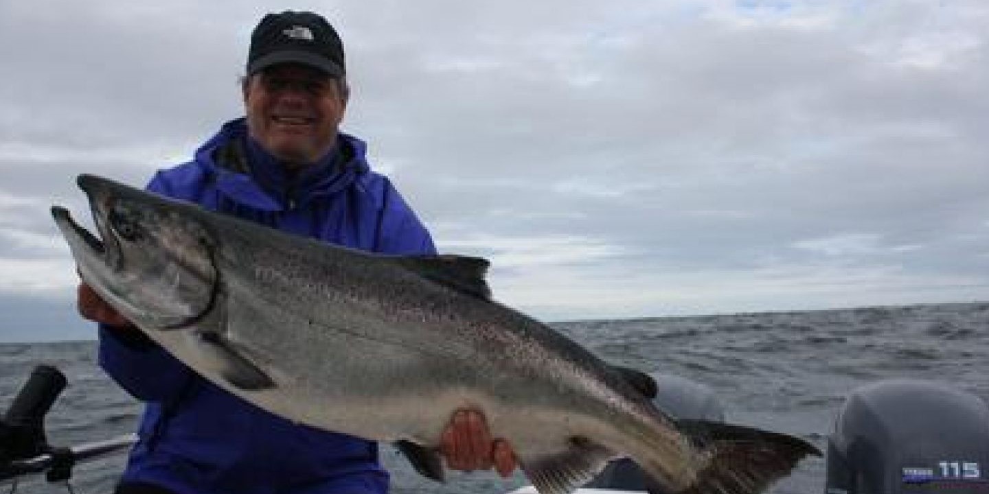 A chinook salmon being held by two people in Tofino