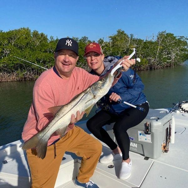 A fisherman holding a 22-inch catch while standing in FL