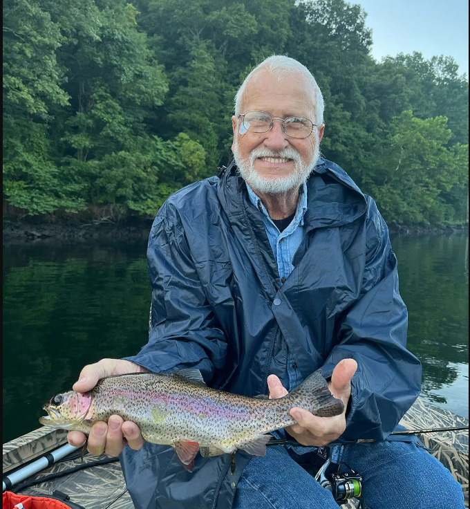 A fisherman proudly holding a rainbow trout caught in Branson