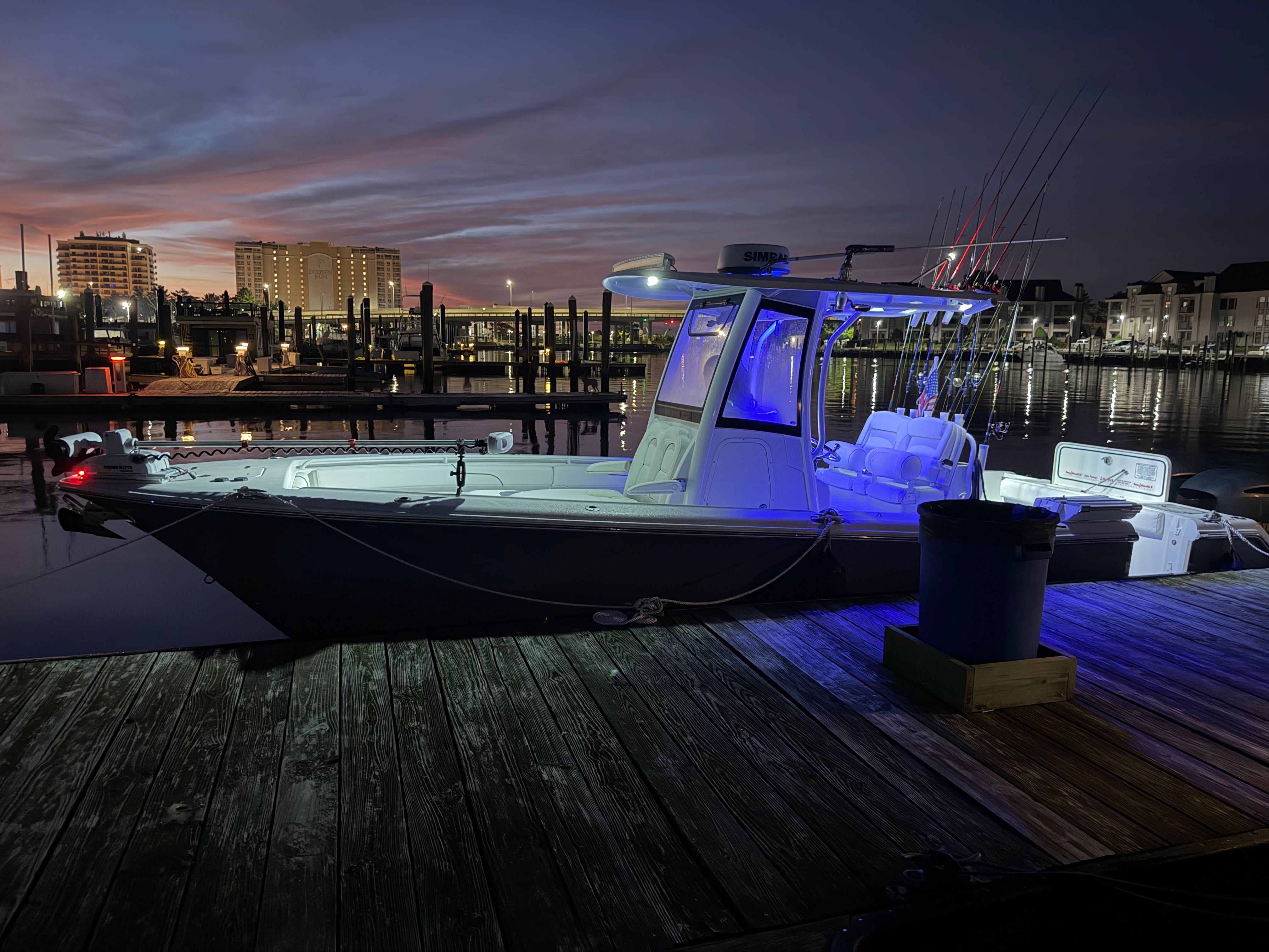 Fishing charter boat docked at marina with blue cabin lighting at sunset in Virginia Beach VA