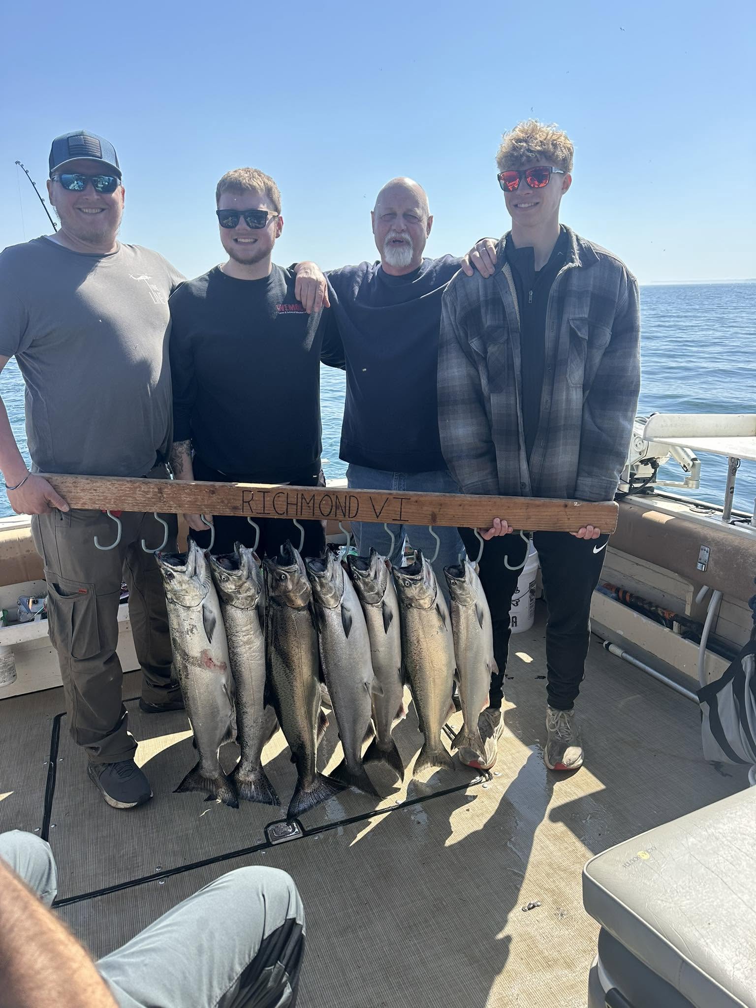 Four anglers displaying their catch of Chinook salmon on fishing boat in South Bristol NY